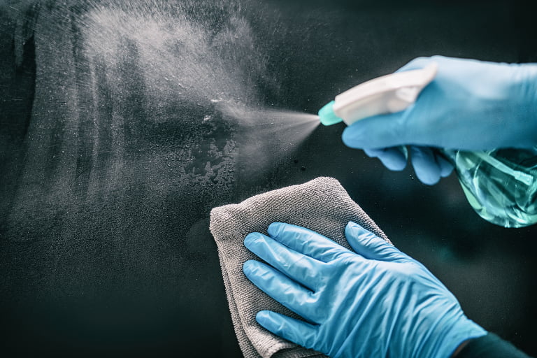 Hands in blue gloves cleaning a surface